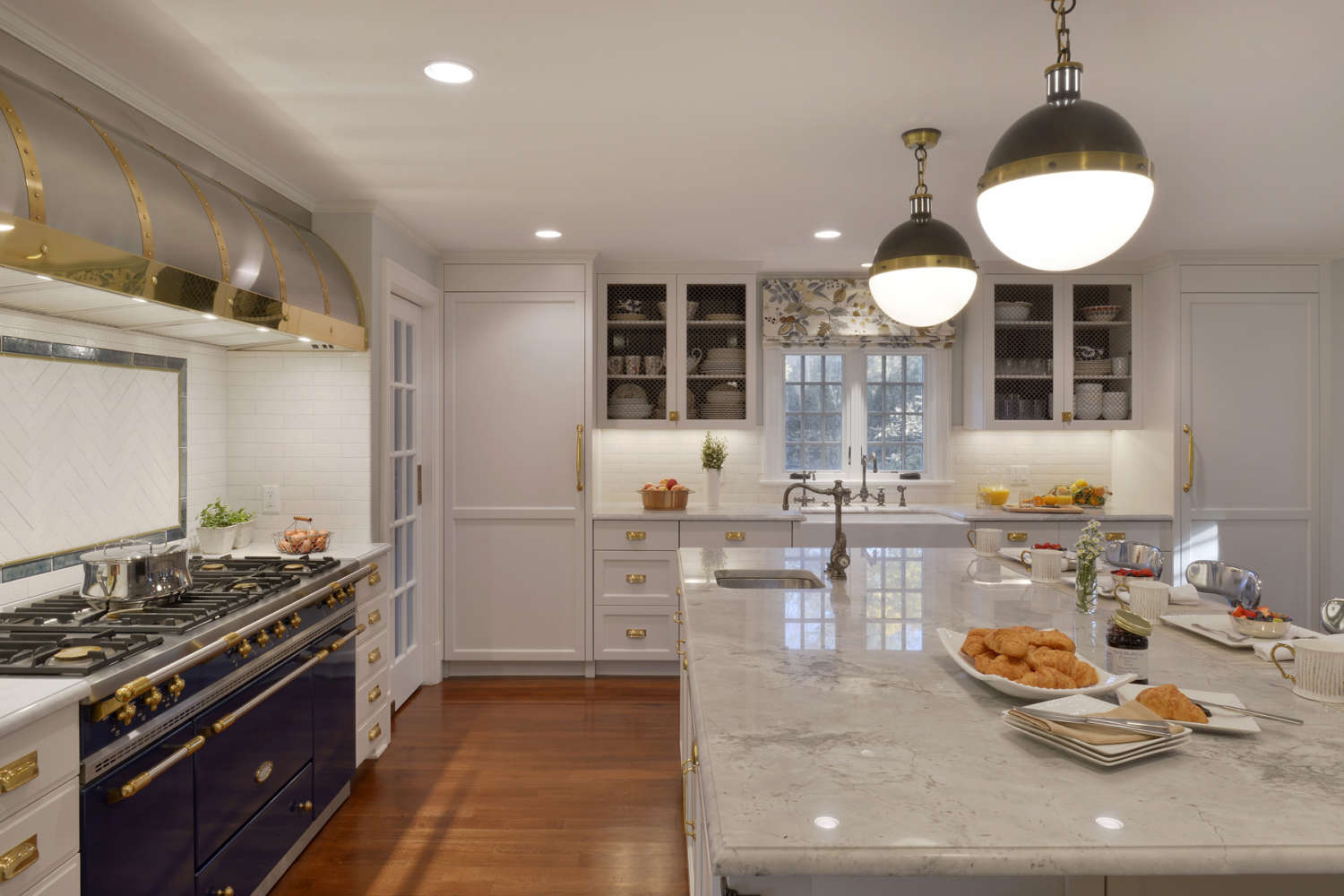 Expansive double island Scarsdale NY kitchen features marble topped center island and Bilotta cabinetry in Paperwhite with brass hardware.