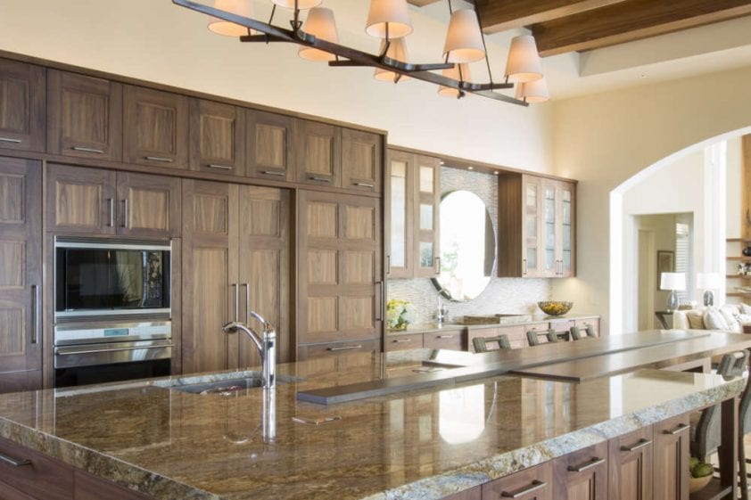 Transitional kitchen features high ceilings with exposed beams, fully custom natural walnut, frameless shaker style Rutt Regency Cabinetry, a large island with seating and warm-toned polished granite countertops. Design by RitaLuisa Garces of Bilotta Kitchens.