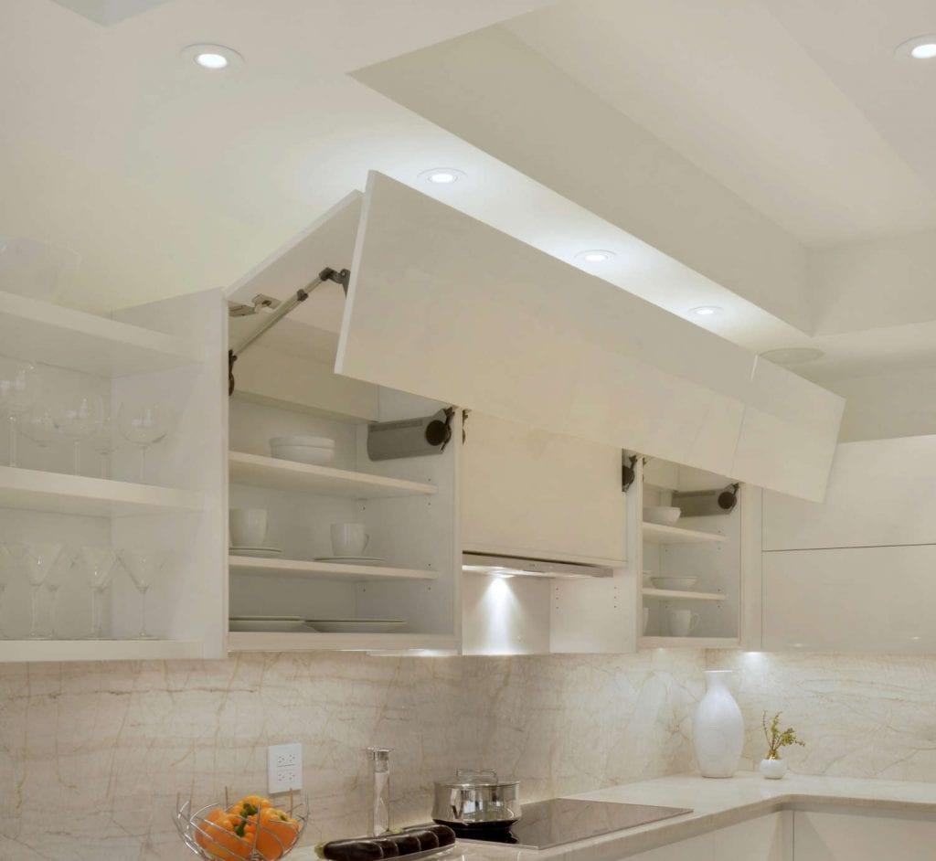 Motorized white high-gloss cabinets has lift-up doors above sink to reveal dishes.