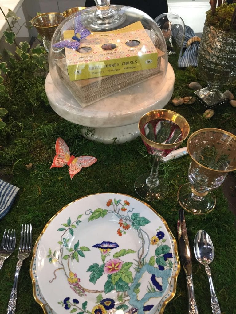 An Art of The Table tablescape set on moss with butterfly accents.