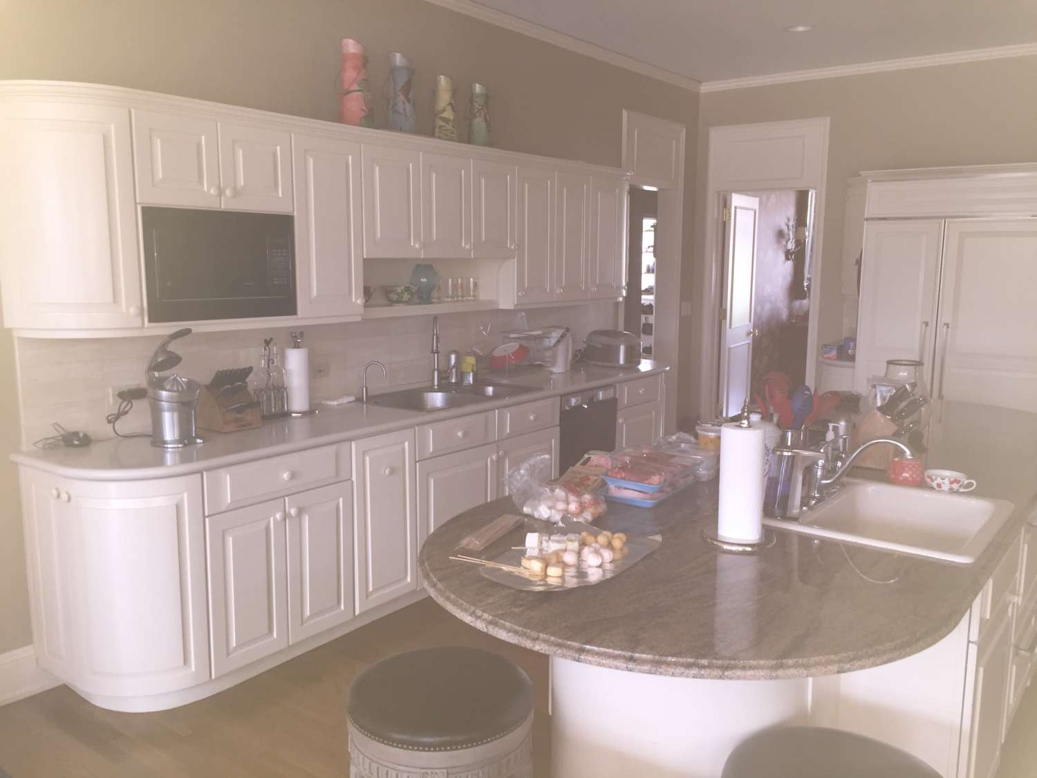 Before picture of dark kitchen with white cabinets and brown granite topped island.