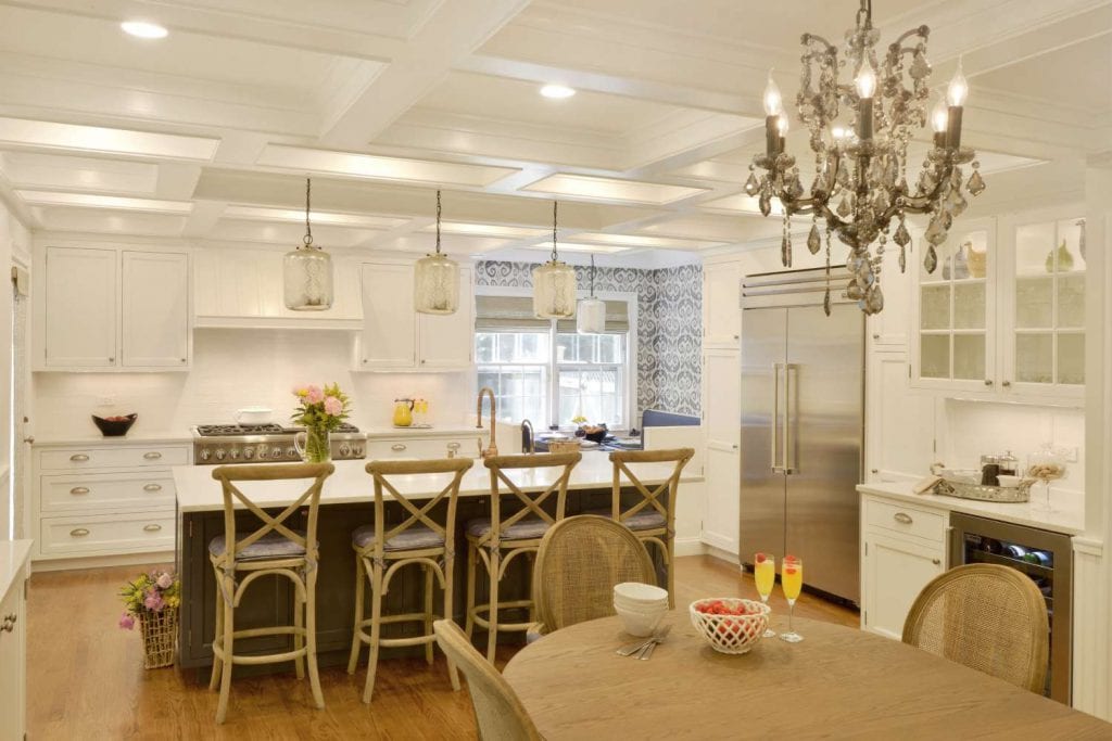 Elegant kitchen features Bilotta Island in Hale Navy, white cabinetry, coffered ceiling and antique chandelier.