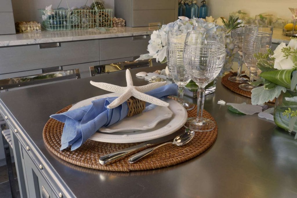 Closeup of seaside luncheon theme tablescape with starfish, wicker charger and Ralph Lauren stemware.