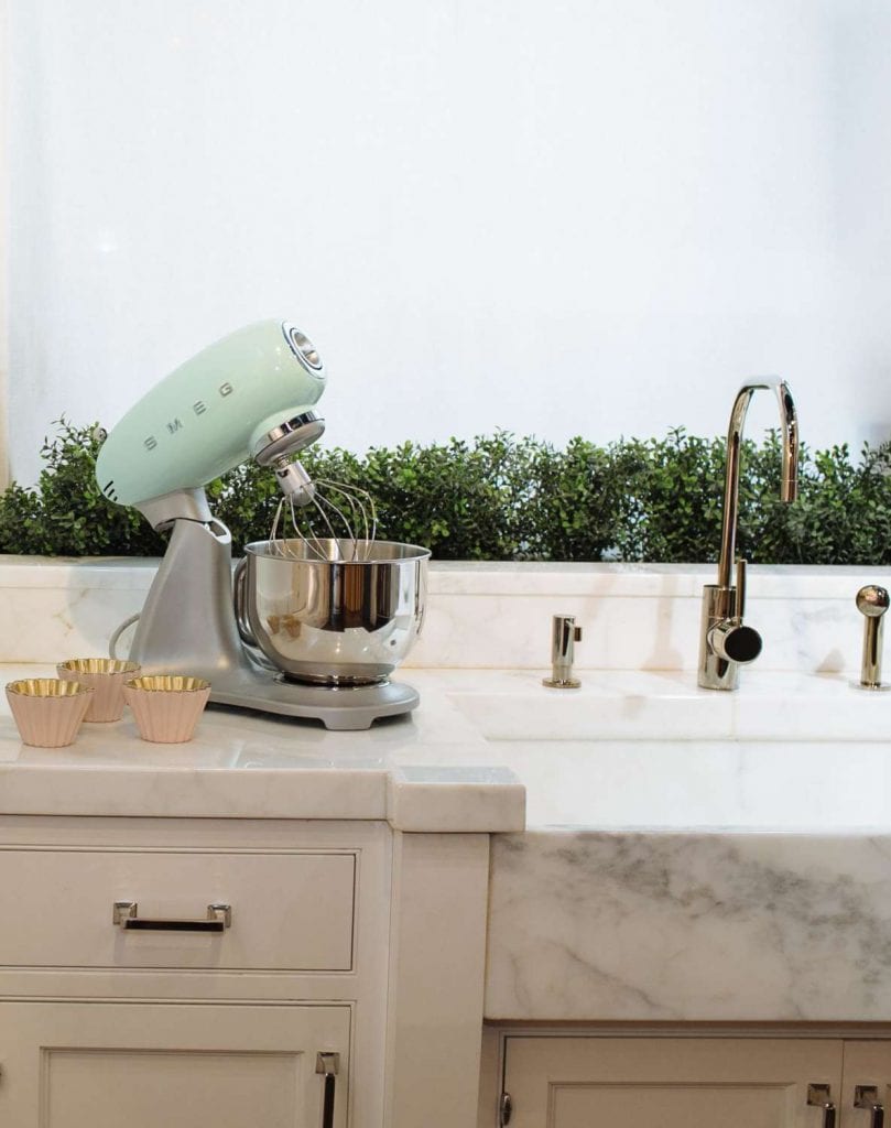 mint-green smeg stand mixer sitting on a marble countertop