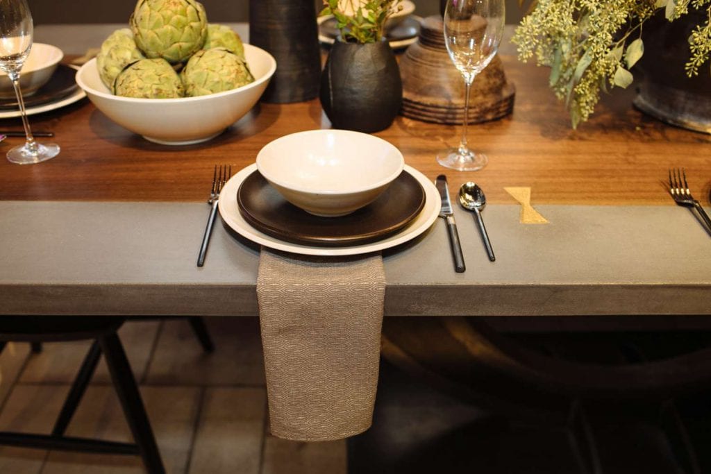 place setting of Calvin Klein’s Cargo collection in beige and brown on a wood and concrete table