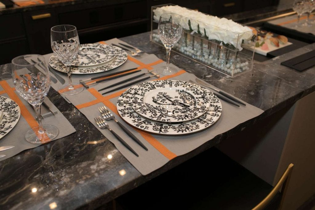 China featuring a stylized motif of birds and trees called Taika Black by Iittala coupled with grey and orange place mats and stainless steel and resin flatware