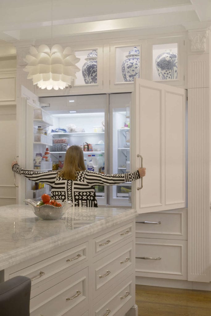 Woman Standing in Front of Open Refrigerator concealed by Bilotta cabinetry