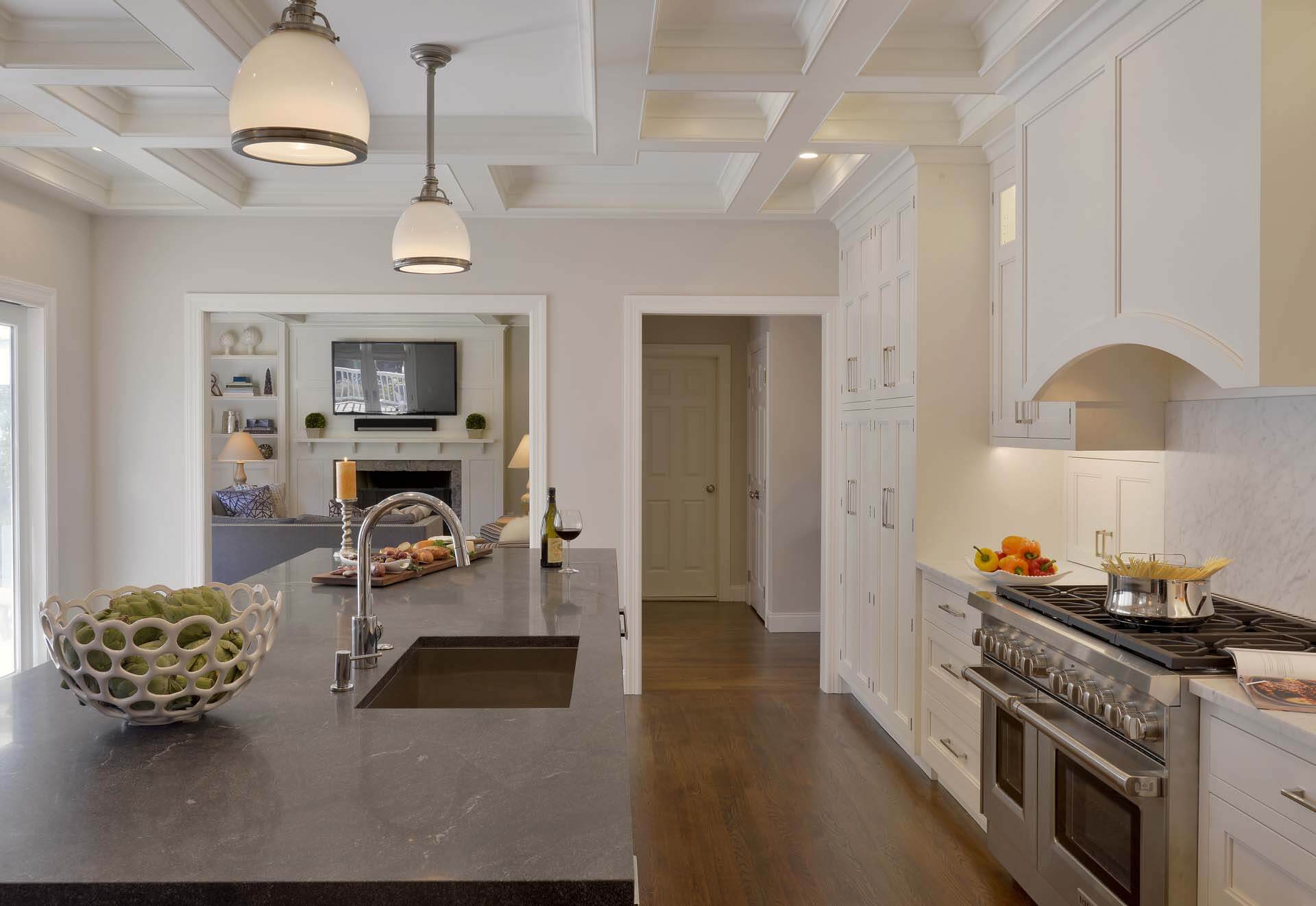 Long, narrow kitchen features Dove White Bilotta cabinetry with stepped door and Carrera marble countertop.