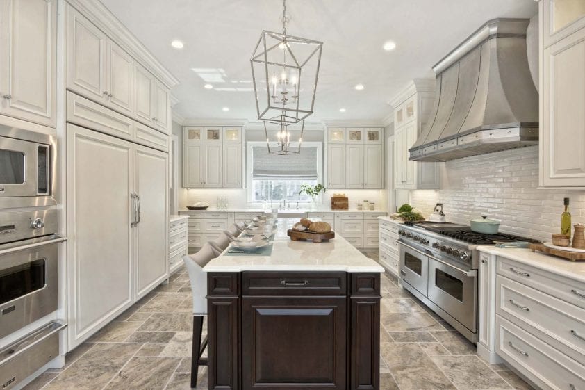 Kitchen features silver pendants, marble-topped cherry island, travertine flooring and white Bilotta cabinetry.