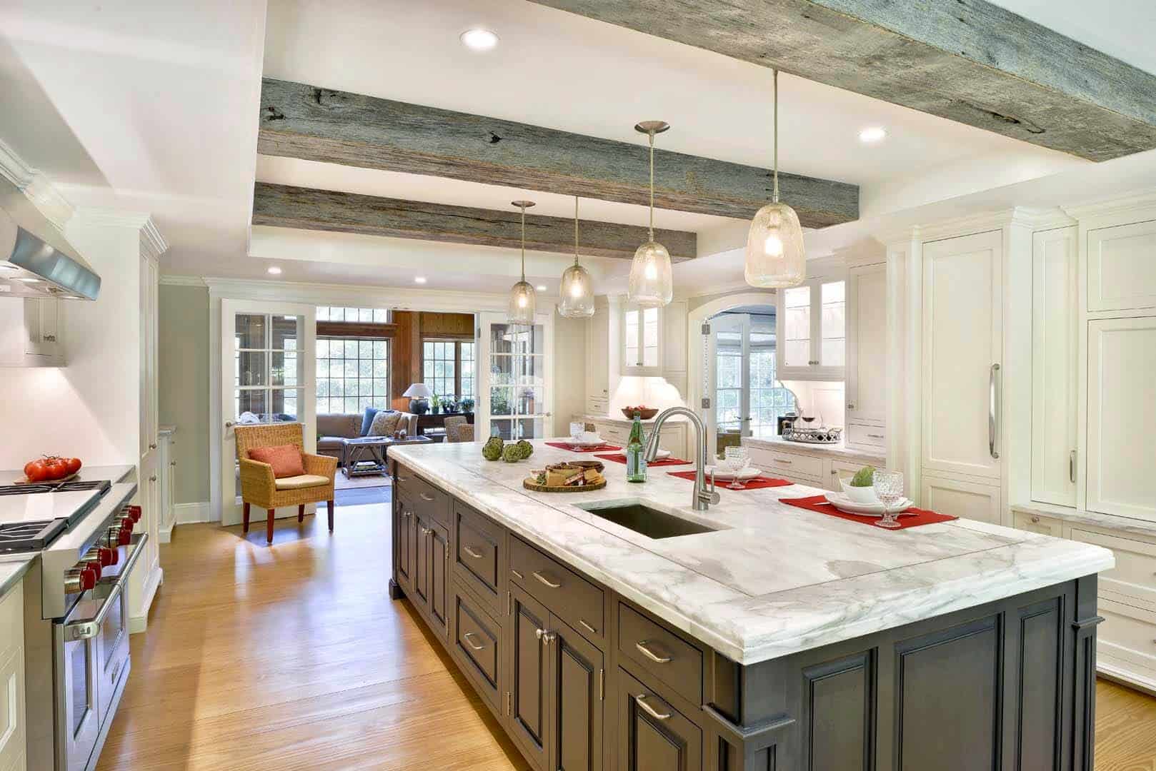 Expansive kitchen in Waccabuc NY features exposed beams, white Bilotta cabinetry and large grey island with marble top.