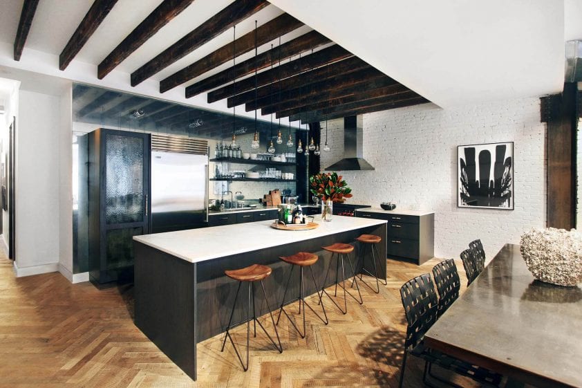 Contemporary NYC loft kitchen has exposed beams, large island with seating and industrial pendant lights.
