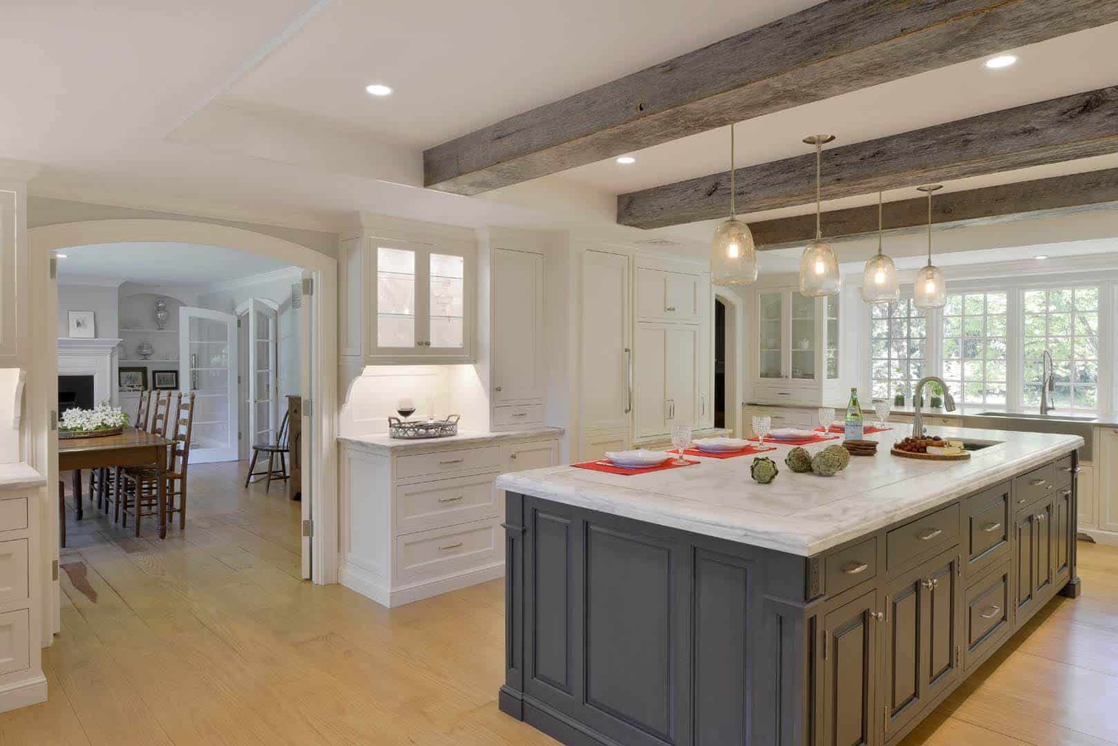 Expansive Waccabuc kitchen features exposed beams, white Bilotta cabinetry and large grey island with marble top.