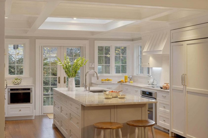 Elegant light-filled kitchen features Super White Rutt cabinetry, quartz countertops and marble subway backsplash.