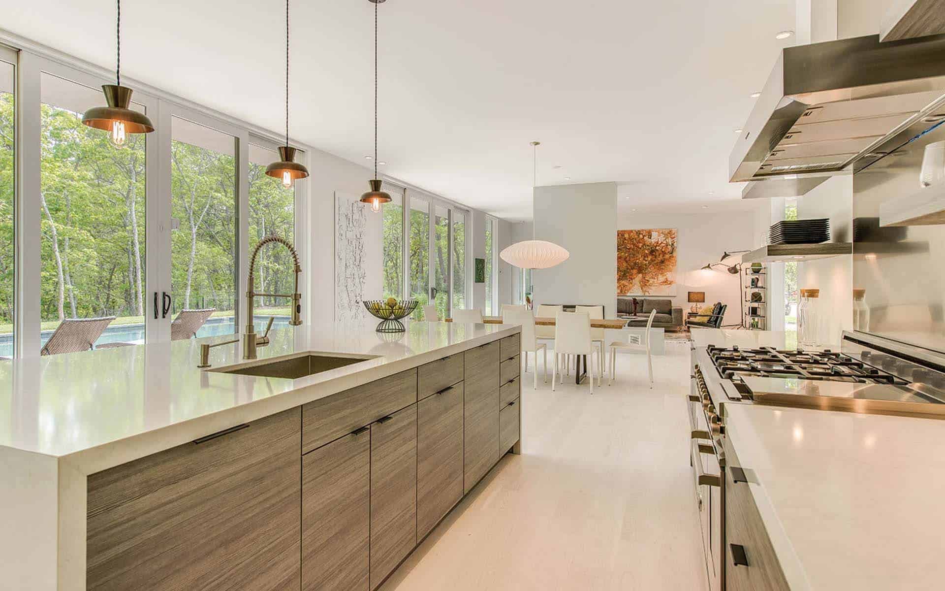 Contemporary Hamptons kitchen features quartz waterfall countertop, Horizontal grained laminate cabinets and matching laminate floating shelves.