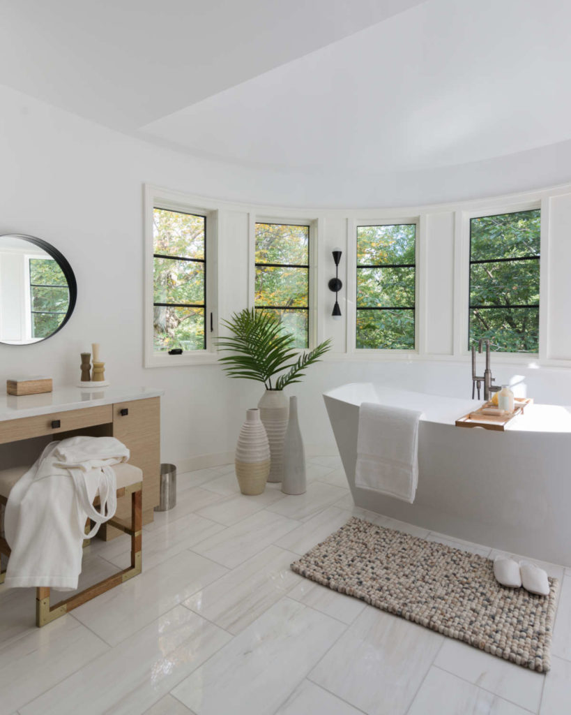 Bathroom features a bank of windows, freestanding tub and custom pale oak cabinetry with bronze hardware.