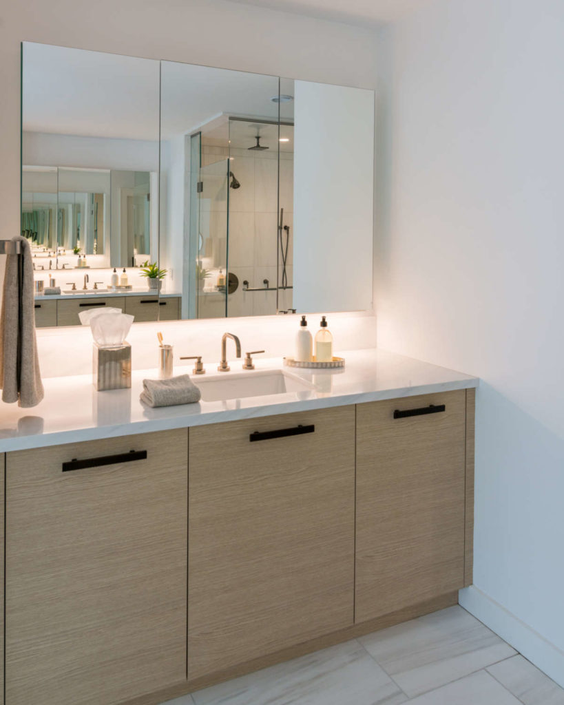 Custom bathroom vanity features laminate with a wood-look matte washed oak finish, granite top and mirror. 