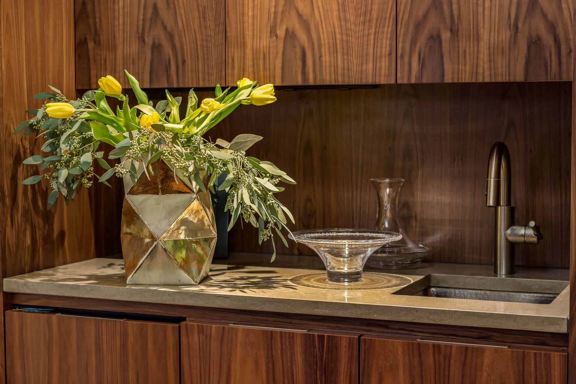 Mid-Century custom wet bar features Bilotta natural walnut cabinetry and backsplash with Lagos Azul honed limestone countertop.