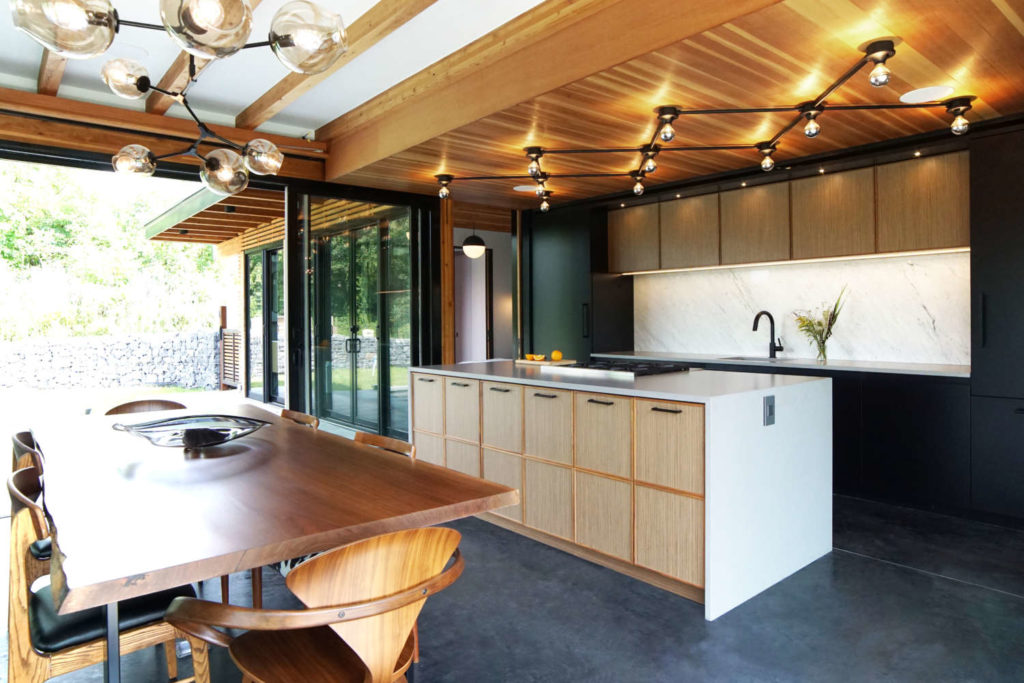 Mid-century modern kitchen features natural heart pine ceiling planks and walnut quarter-sawn veneer cabinetry.