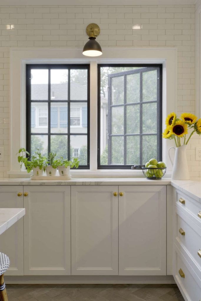 Classic White Kitchen features white glazed tile walls and brass accents