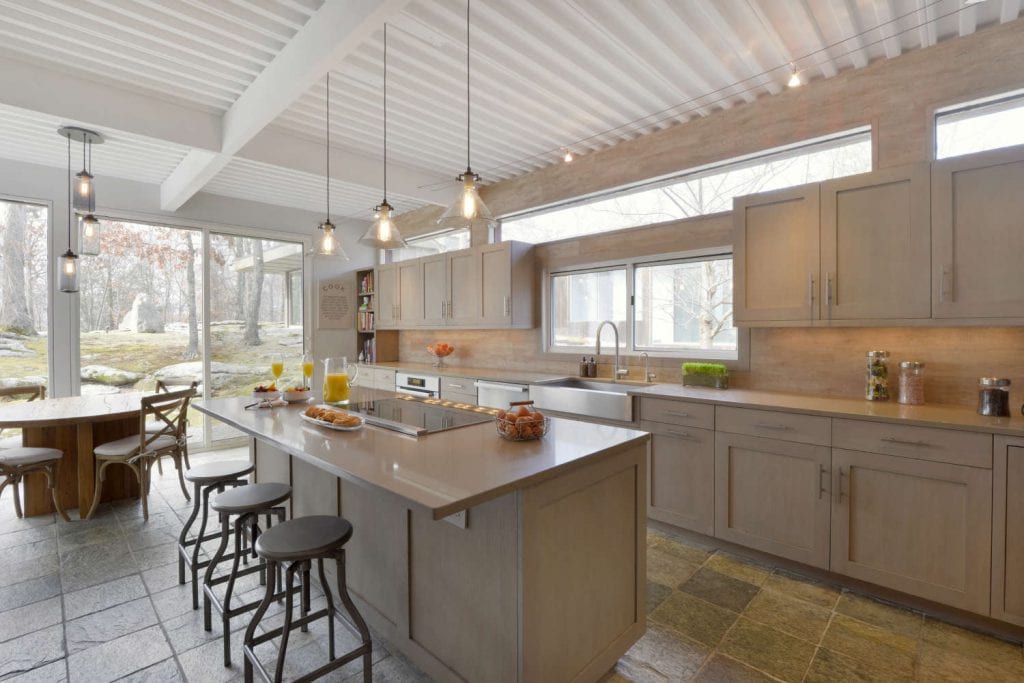 Contemporary kitchen features white-painted beams and rafters, floor-to-ceiling windows and a center island with seating.
