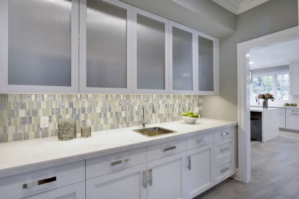 Clean and classic all-white butler's pantry features white diamond marble countertop and white Bilotta cabinetry.