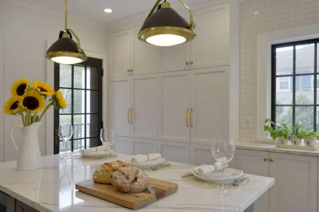 Quartz topped grey kitchen island is lit by grey and brass pendants.