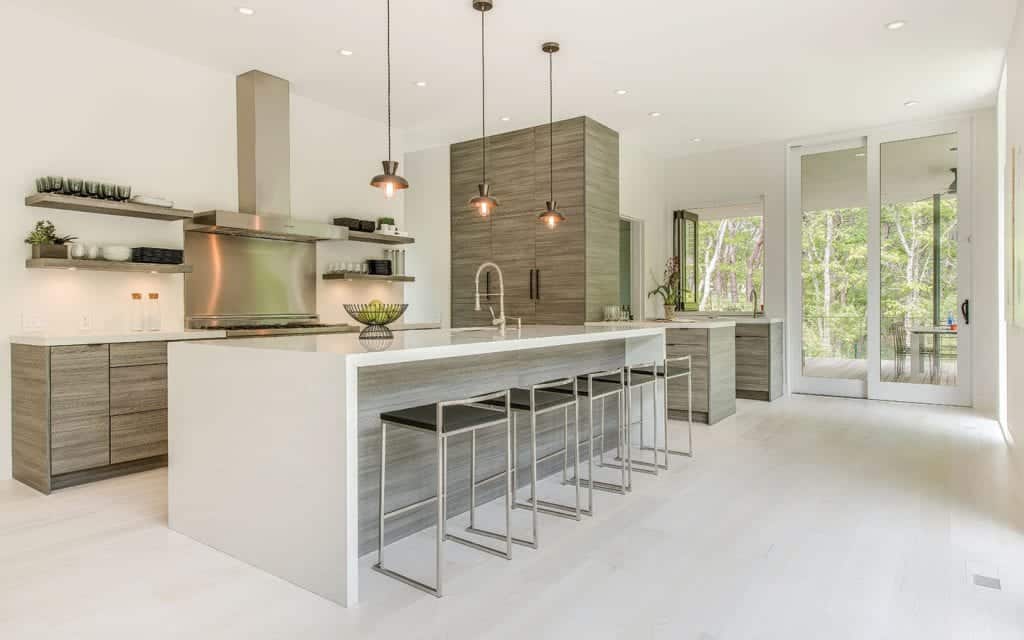 Contemporary Hamptons kitchen features quartz waterfall countertop, Horizontal grained laminate cabinets and matching laminate floating shelves.