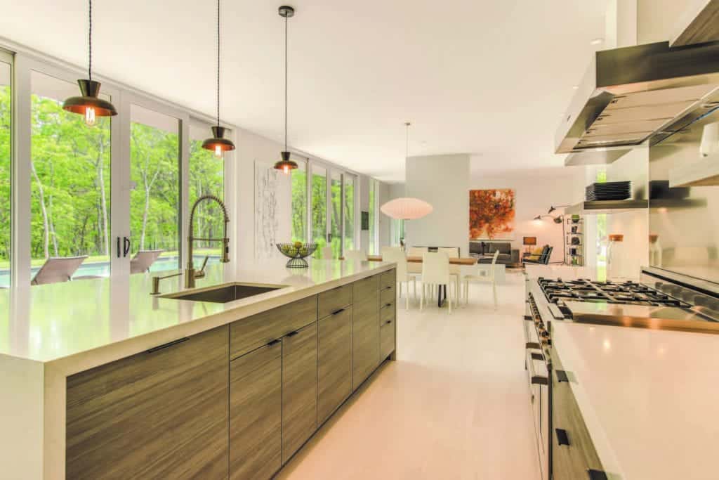 East Hampton open plan kitchen features a large horizontal grained island with waterfall edge quartz countertop.