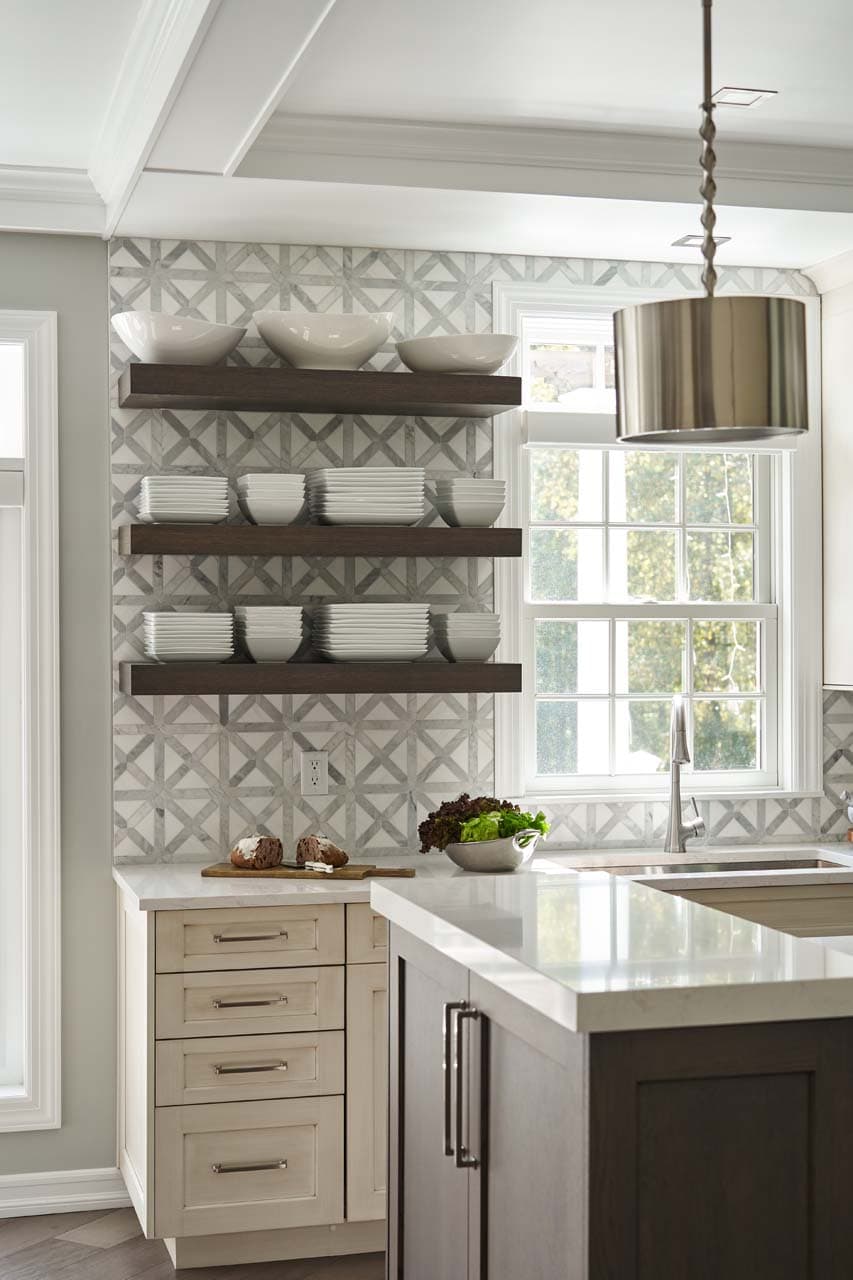 Inviting kitchen features floating shelves and a muted trellis-patterned backsplash tile.
