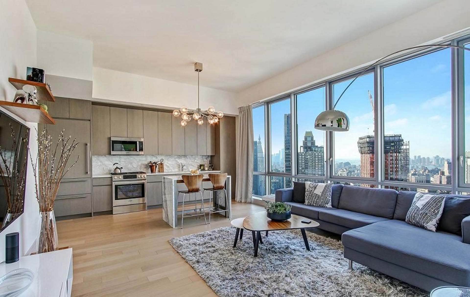 Luxury open-concept penthouse condo features Bilotta Collection kitchen cabinets, large island with seating and NYC skyline view.