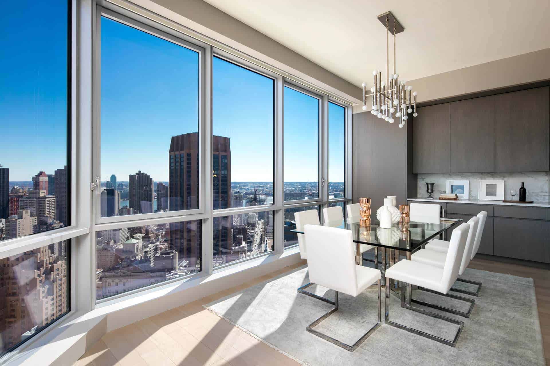 Luxury penthouse kitchen features flat front Bilotta cabinetry, dining area and floor-to-ceiling windows with NYC view.