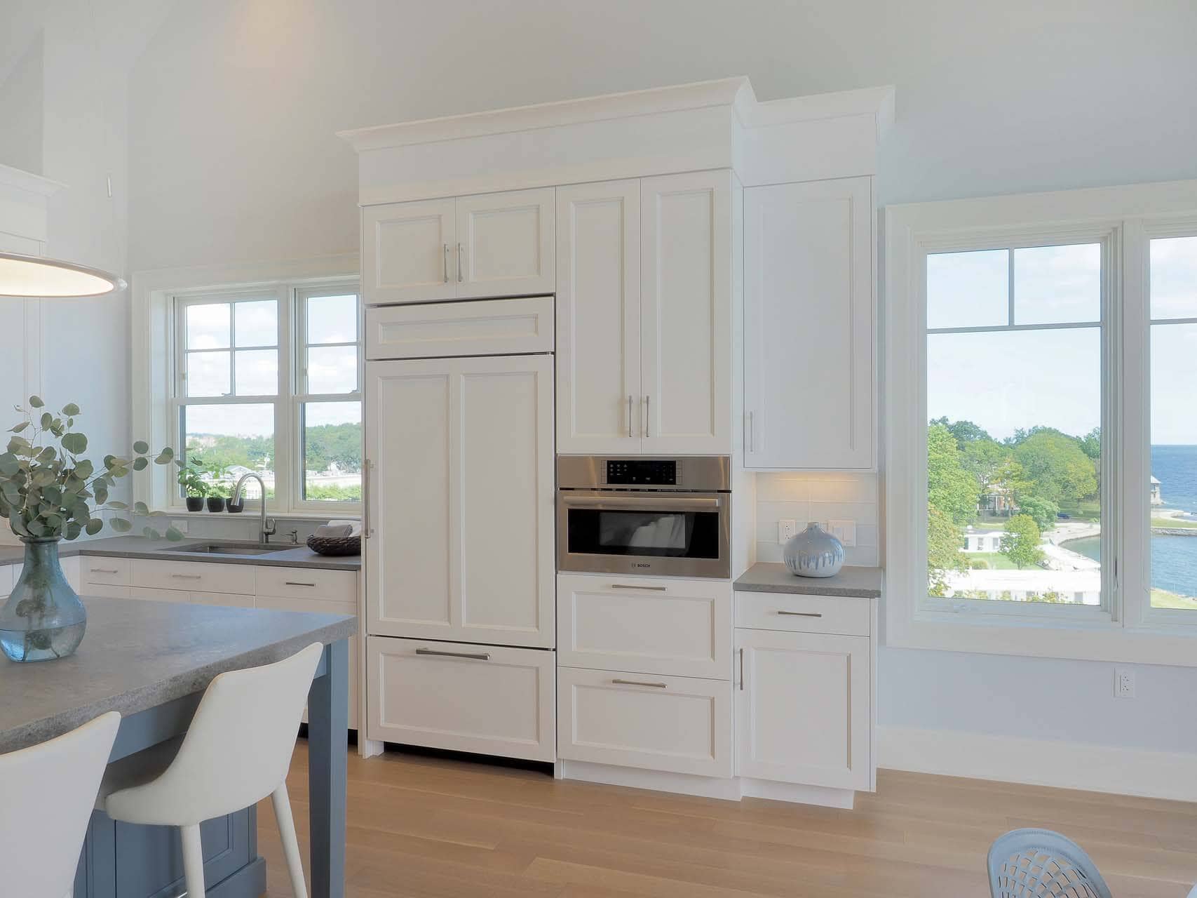 Luxury beachfront condo features oversized windows, pale oak flooring and white and blue-painted Bilotta cabinetry.