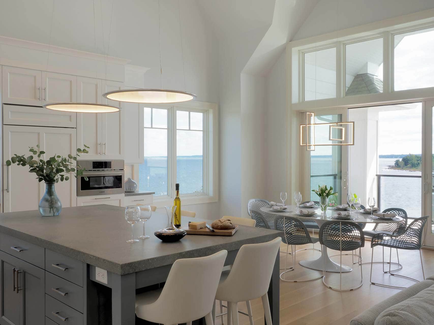 Luxury condo kitchen features granite-topped island with seating, illuminated by contemporary disc-shaped pendants.