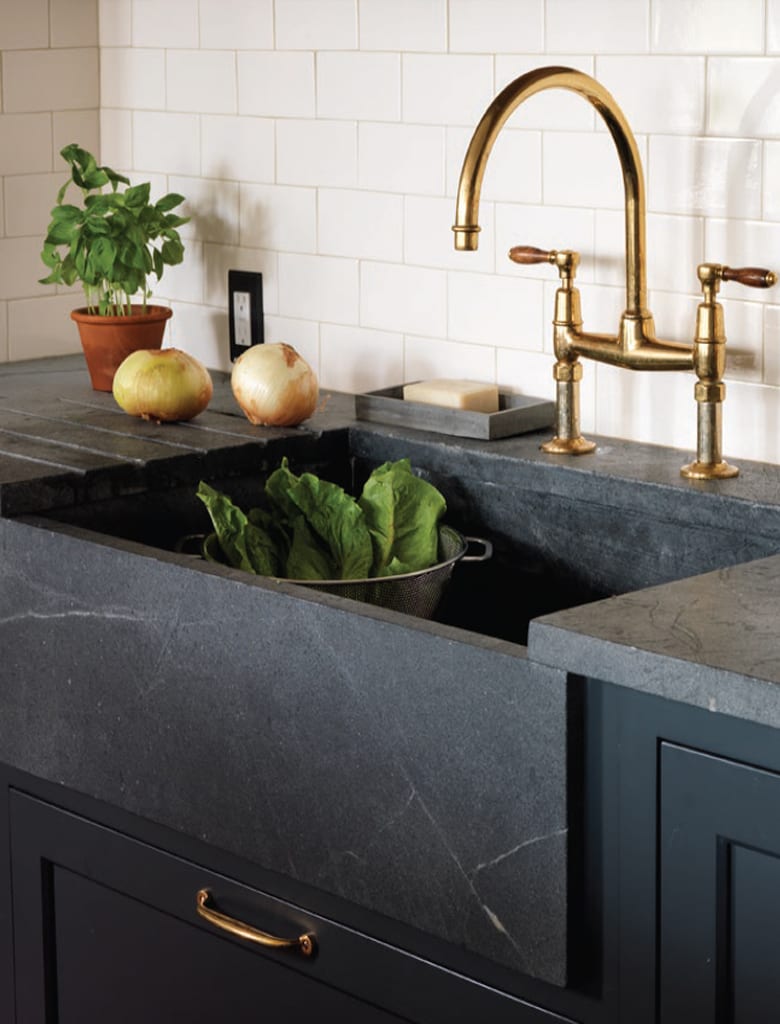 Classic kitchen features farmhouse sink, soapstone counter and apron and blue painted Bilotta cabinets with brass hardware.
