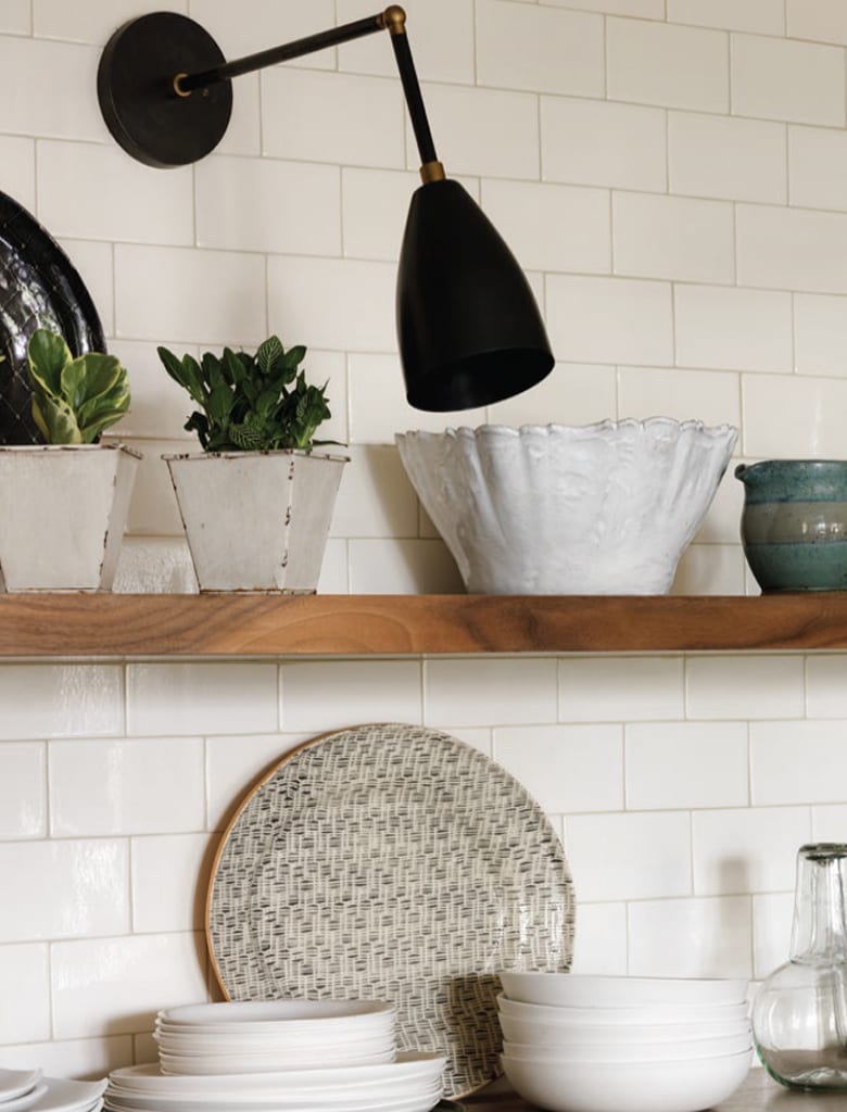 French-style brownstone kitchen features white glazed tile walls and open shelving with black vintage spotlights.