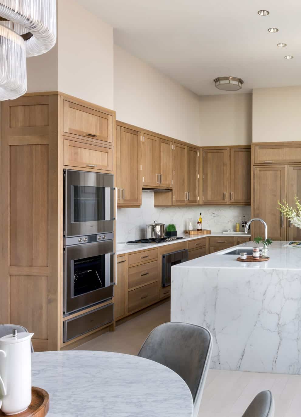 Multi-unit residential kitchen features Bilotta Collection cabinets in rift cut white oak and island with marble waterfall countertop.