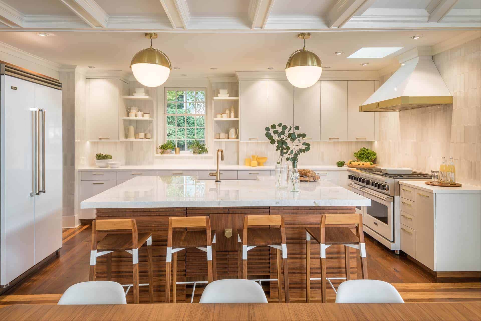 Contemporary kitchen features white Rutt Regency cabinetry, with brass hardware and white marble topped walnut island.