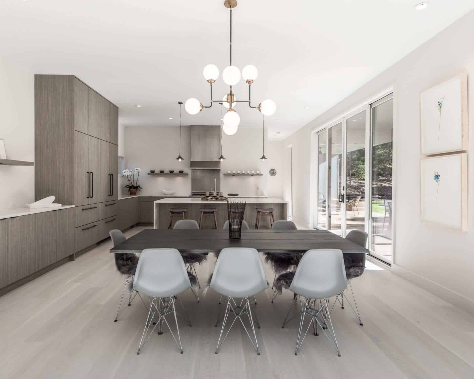 Monochromatic modern kitchen features grey Nantucket vertical laminate Brookhaven cabinetry, custom island and dining area.