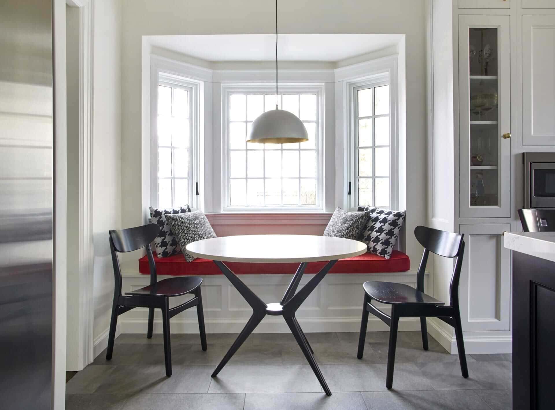 Art Deco inspired kitchen features custom window seat banquette with pendant light and marble bistro table.