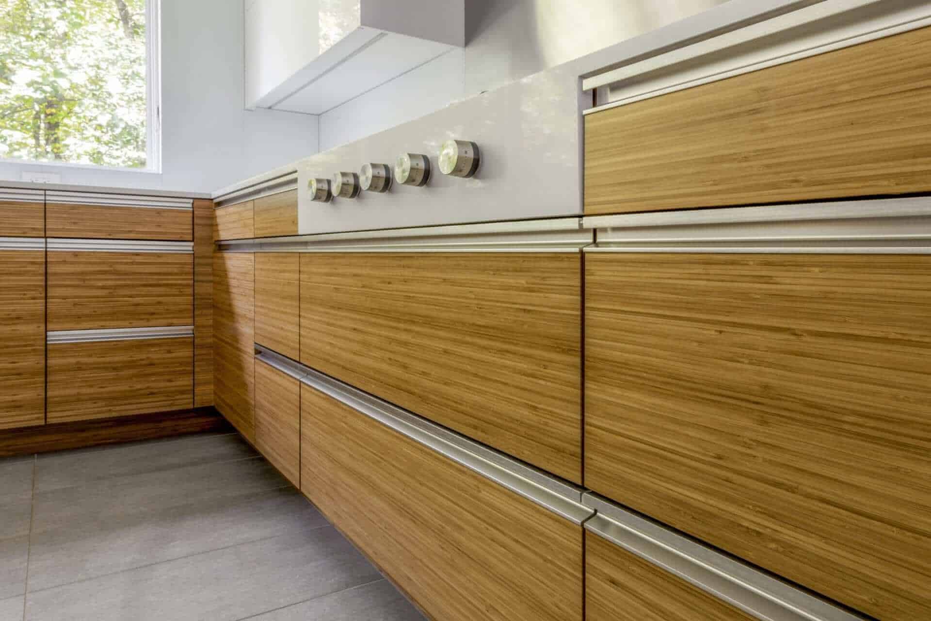 Clean, modern kitchen features NAC cabinets in both bamboo with caramel stain and white gloss, grey flooring and stainless channel hardware.