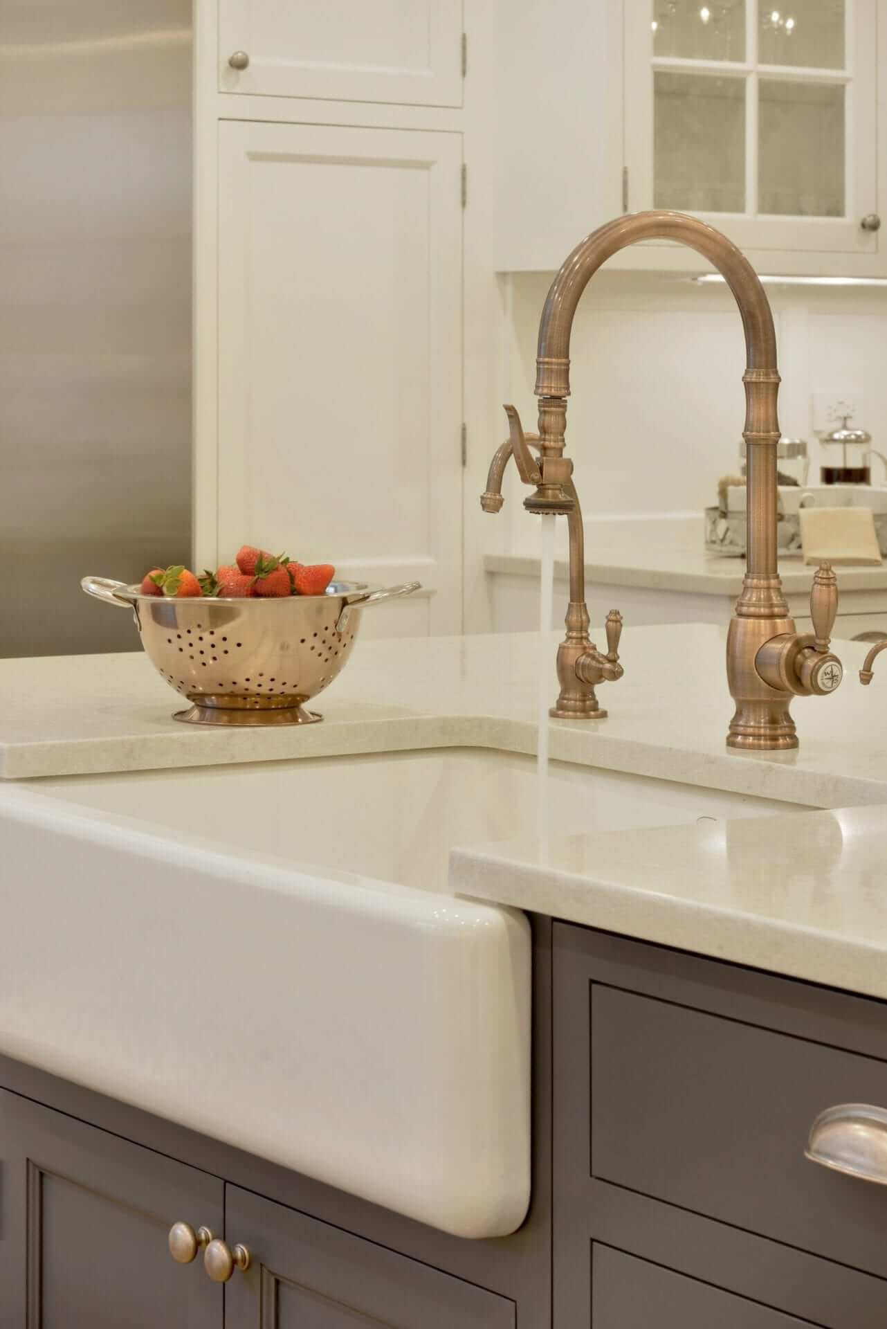 Elegant kitchen with Bilotta cabinetry, white apron sink and brass faucet.