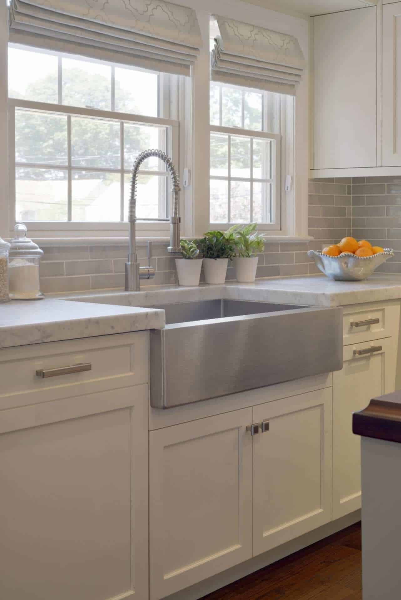Kitchen features Bilotta Signature cabinets, stainless apron sink and grey ceramic tile backsplash.
