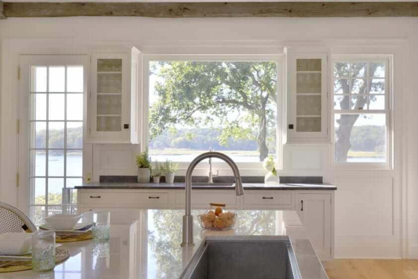 Crisp classic kitchen features stained rift cut white oak island with custom finish and La Dolce Vita quartzite top.