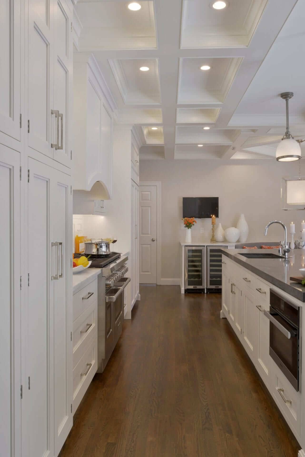 Long, narrow kitchen features Dove White Bilotta cabinetry with stepped door and Carrera marble countertop.