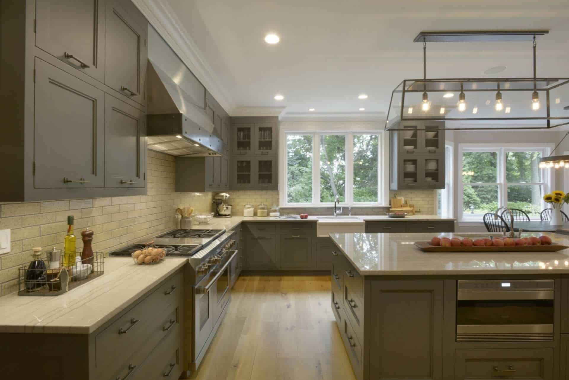 Country kitchen features gray Bilotta cabinetry, White Macambas Caesarstone countertops and a reclaimed barn door.