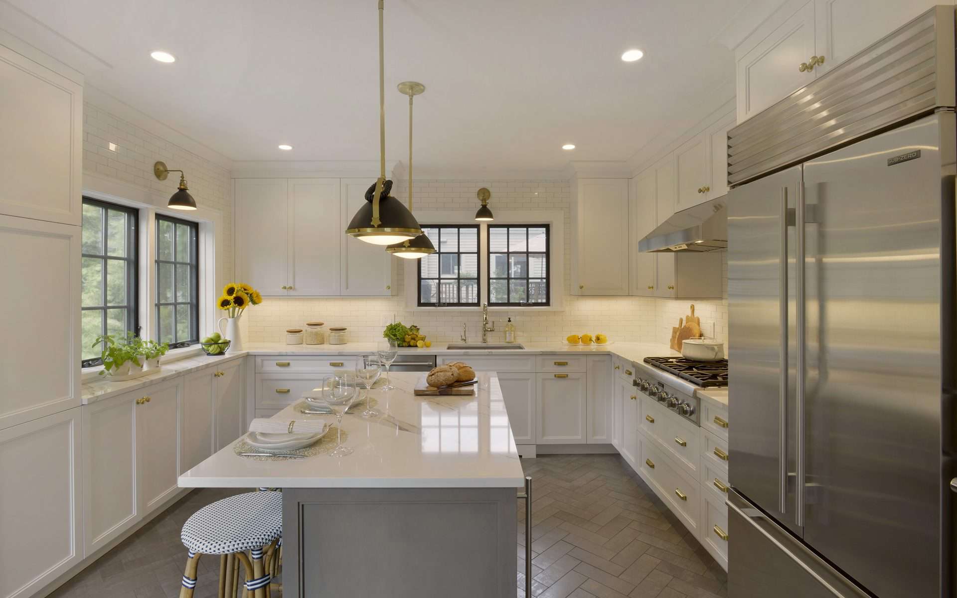 Classic kitchen features white Bilotta cabinetry, custom gray island, gold accents and modern pendant lights.