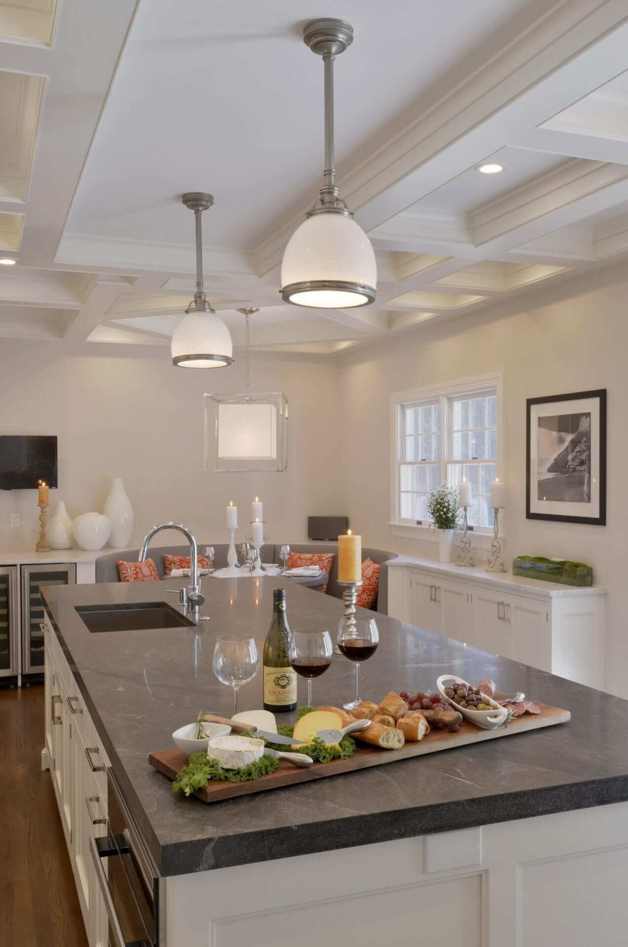 Long, narrow kitchen features white Bilotta cabinetry and semi-circular banquette and built-in wine fridge.
