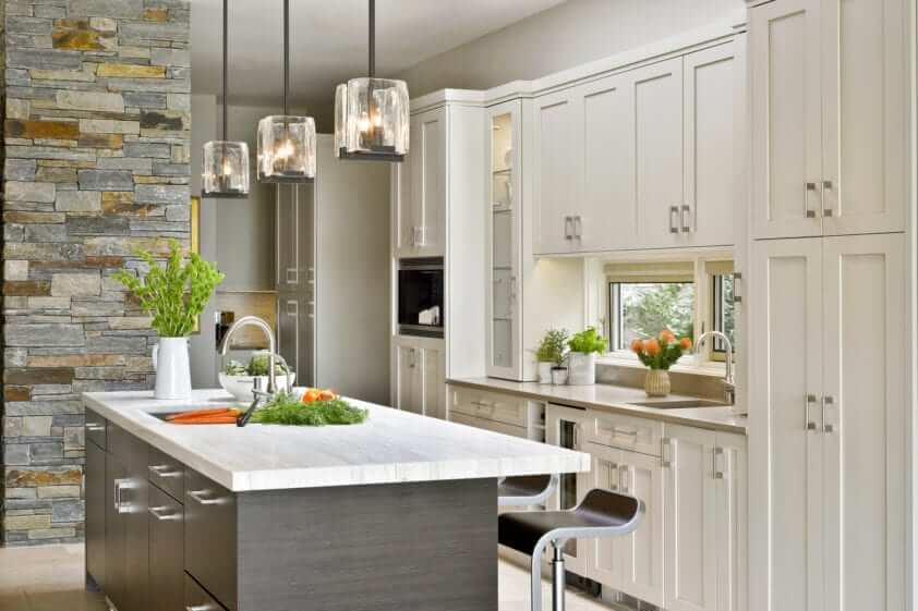 Artcraft Moveno horizontal grained island with quartz top is accented by glass cube pendant lights.