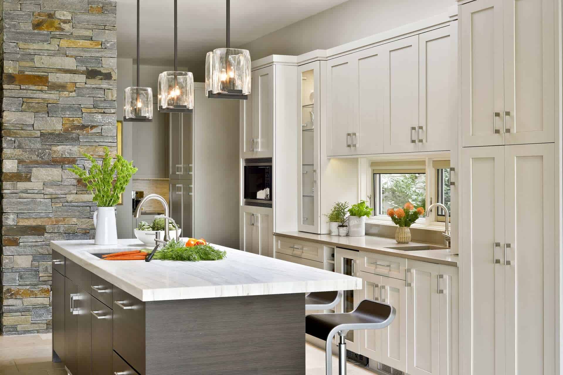 Artcraft Moveno horizontal grained island with quartz top is accented by glass cube pendant lights.
