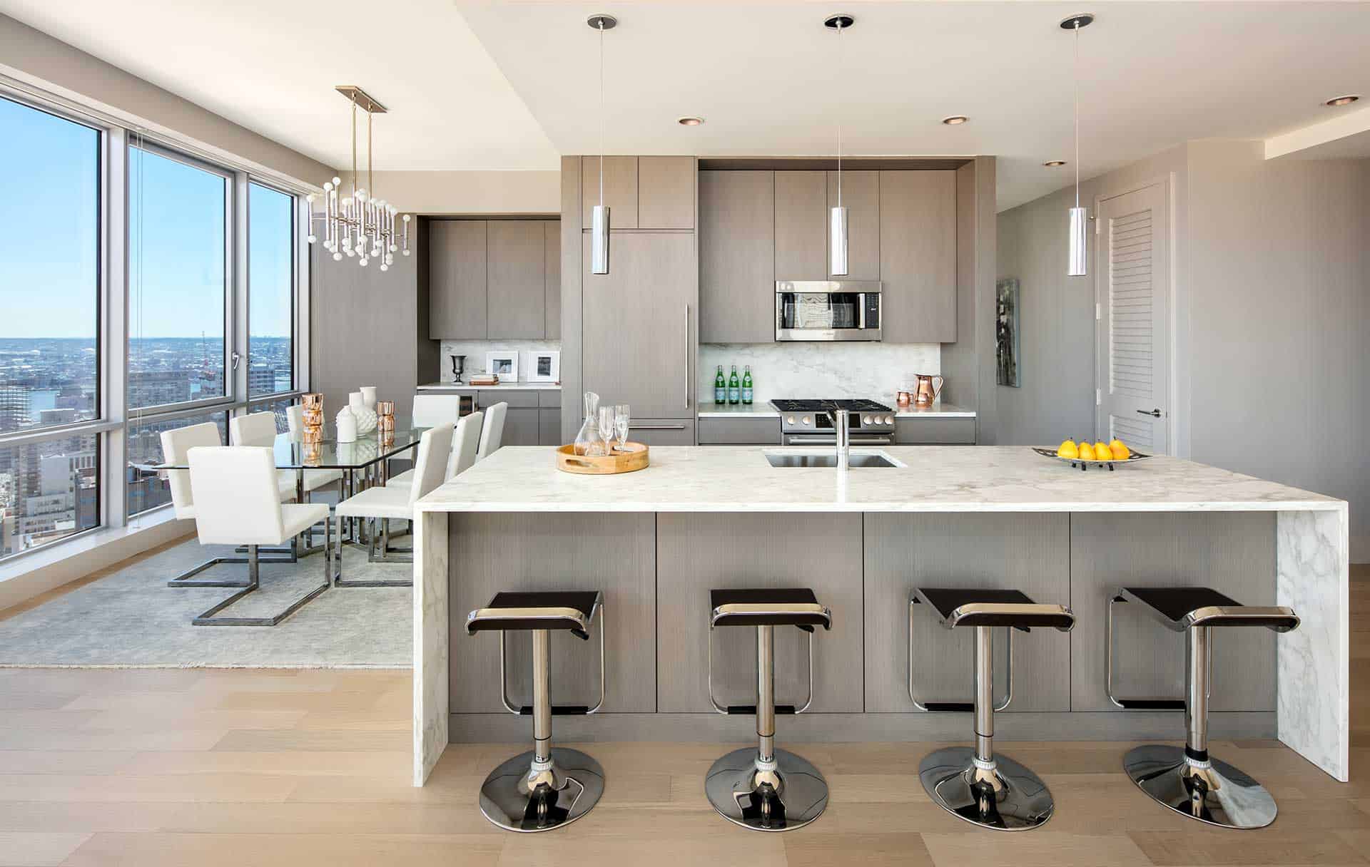 Modern luxury penthouse kitchen features Bilotta cabinetry, with washed finish and island with marble waterfall countertop.